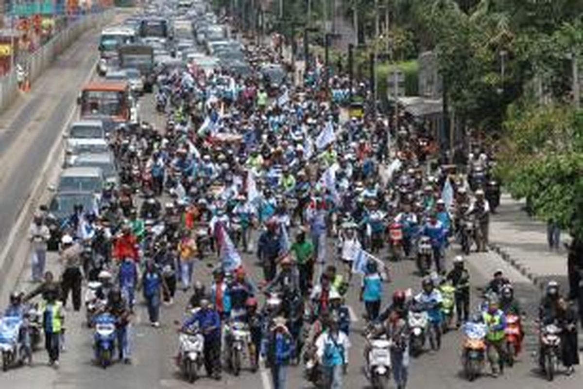 Massa buruh mendorong sepeda motor dalam unjuk rasa di Bundaran Hotel Indonesia, Jakarta Pusat, Rabu (10/12/2014), sebagai bentuk protes terhadap kenaikan harga BBM.
