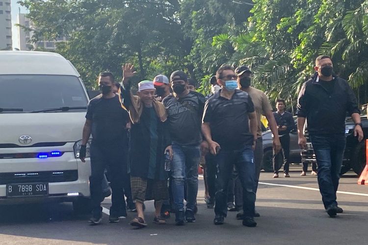 Pimpinan kelompok Khilafatul Muslimin Abdul Qadir Hasan Baraja melambaikan tangan untuk menyapa para simpatisannya saat tiba Mapolda Metro Jaya, Selasa (7/6/2022)