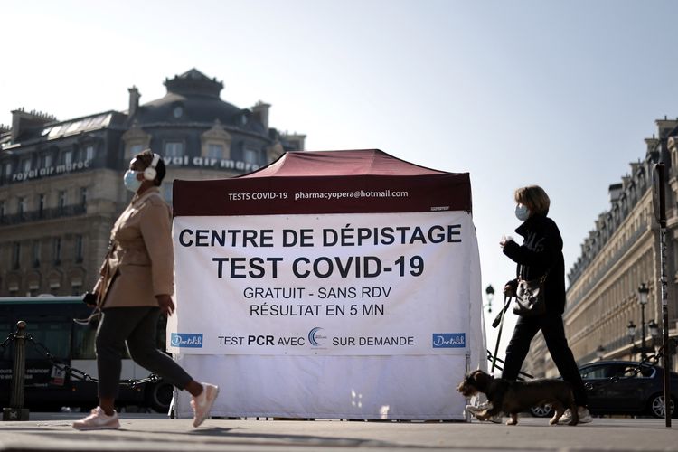 This file photo taken on March 31, 2021 shows people walking past a tent where patients undergo an antigenic coronavirus test, at the Opera square in Paris amid the spread of the COVID-19  pandemic. - As of October 15, Covid-19 tests will no longer be repay except on medical grounds or for those who have been vaccinated. (Photo by Thomas COEX / AFP)