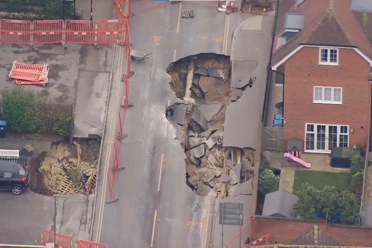 Tangkapan layar dari video yang menunjukkan sinkhole atau lubang ambles besar di jalan Desa Godstone, Inggris tenggara. Lubang ini muncul pada Senin (17/2/2025) dan terus melebar sampai 20 meter hingga Rabu (19/2/2025).