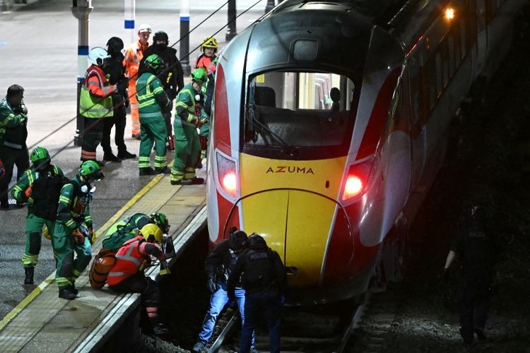 Petugas polisi dan anggota layanan darurat menyisir rel di bawah kereta LNER Azuma di Stasiun Huntingdon di Huntingdon, Inggris timur, pada 1 November 2025, menyusul penusukan massal di dalam kereta. Kepolisian Inggris mengatakan mereka telah menangkap dua tersangka pada Sabtu ketika sejumlah orang dibawa ke rumah sakit setelah penusukan di dalam kereta di Cambridgeshire, Inggris timur.