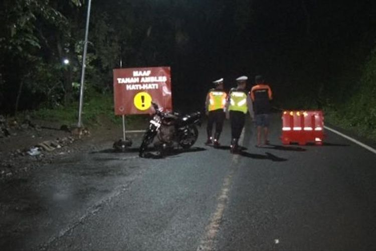Petugas Polisi Lalu lintas memasang blokade di lokasi longsor yang terjadi di Kilometer-16, desa Nglinggis Kecamatan Tugu Trenggalek Jawa Timur (12/02/2017)