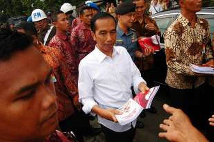 Presiden Joko Widodo membagikan buku kepada warga Kampung Pulo Geulis , Keluarahan Babakan Pasar, Kecamatan Bogor Tengah, Kota Bogor, Selasa (28/6/2016).