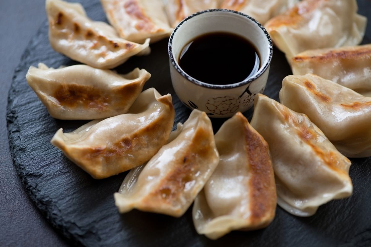 Ilustrasi gyoza khas Jepang dengan saus cocolan. 