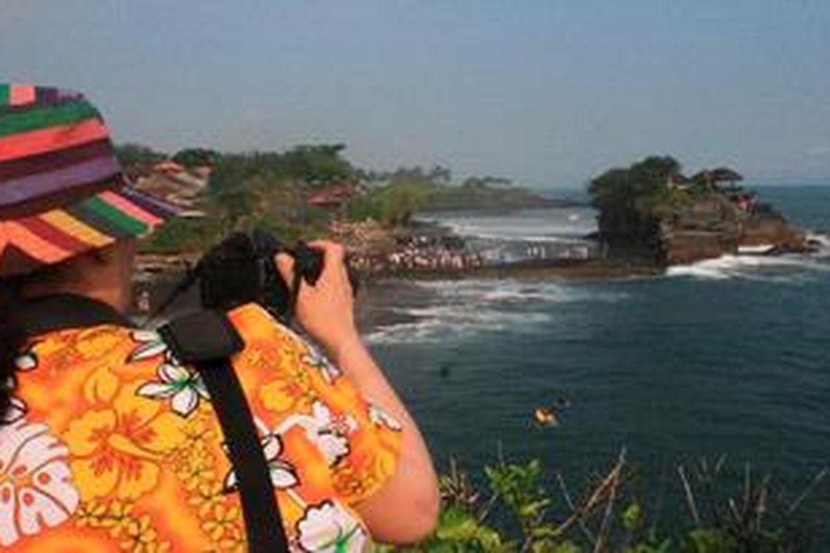 Seorang wisatawan asing tengah mengabadikan panorama wisata Pura Tanah Lot, Kabupaten Tabanan, Bali, Sabtu (9/6/2012) sore. Tanah Lot menjadi salah satu favorit kunjungan turis asing dan domestik setelah Pantai Kuta, Kabupaten Badung. Tahun lalu, sedikitnya dua juta pengunjung mendatangi Tanah Lot dari rata-rata hariannya sekitar 700-an orang. Liburan tahun ini diperkirakan bisa mencapai lebih dari 10.000 pengunjung per hari.  
