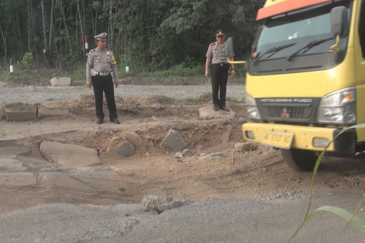 Sebuah truk melintas dengan hati-hati di jalan berlubang besar tepat di hadapan Kapolres Prabumulih yang tengah memeriksa kondisi jalan tersebut.