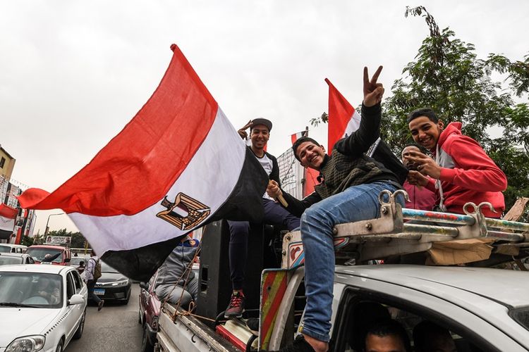 Sekelompok warga Mesir membawa dan membentangkan bendera Mesir.
