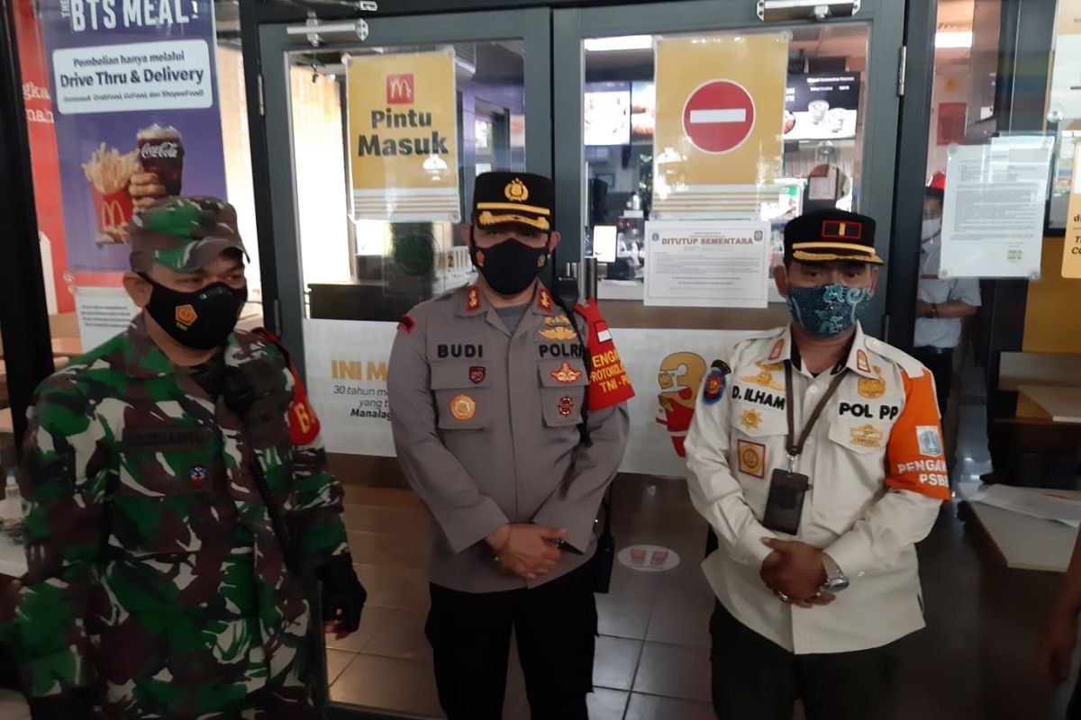 Petugas kepolisian segel McDonald's Stasiun Gambir karena mengundang kerumunan yang disebabkan oleh promo BTS Meal, Rabu (9/6/2021).