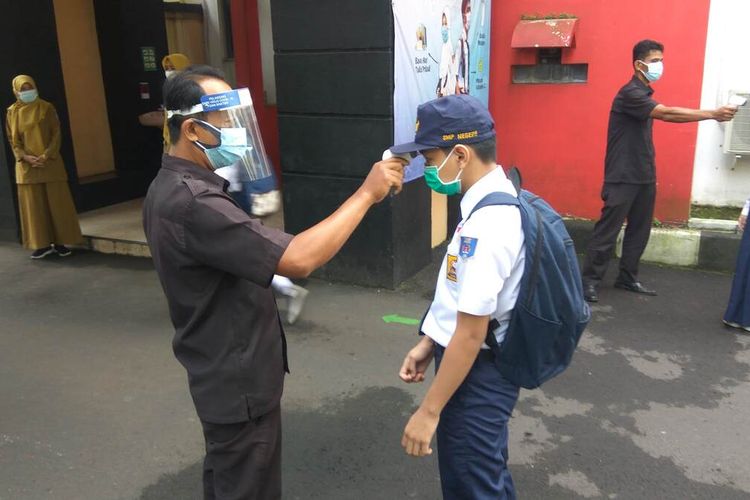 Siswa menjalani cek suhu tubuh di gerbang masuk SMPN 1 Ciamis, Senin (19/4/2021).