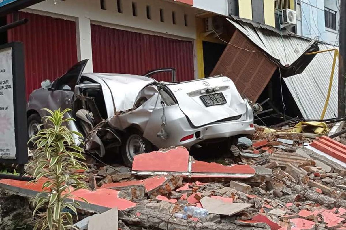 Sebuah mobil dan bangunan rusak akibat gempa bumi, di Mamuju, Sulawesi Barat, Jumat (15/1/2021). Petugas BPBD Sulawesi Barat masih mendata jumlah kerusakan dan korban akibat gempa bumi berkekuatan magnitudo 6,2 tersebut.