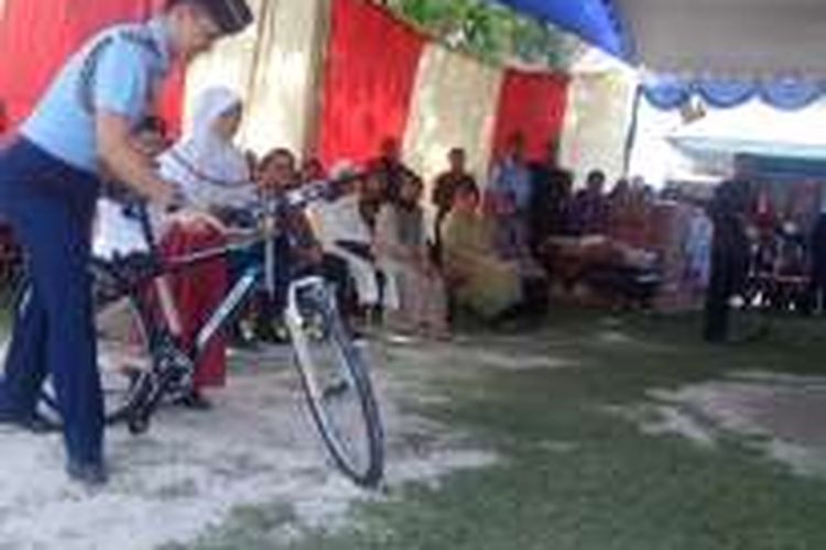 Tuntun sepeda-Ajudan Presiden Jokowi, Lettu Luqman menuntun sepeda hadiah untuk siswi sd kelas empat Sd Karangpatihan, Dina Wardani (berjilbab,red) setelah berhasil menjawab pertanyaan orang nomer satu di Indonesia itu, Senin (19/6/2016) sore. 