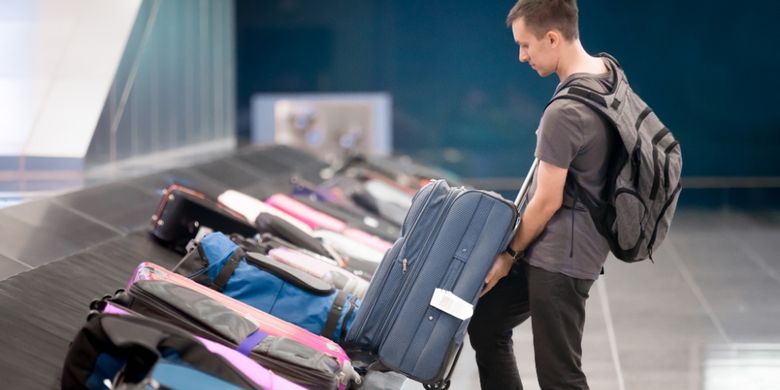ILUSTRASI - Penumpang mengambil koper di bandara.