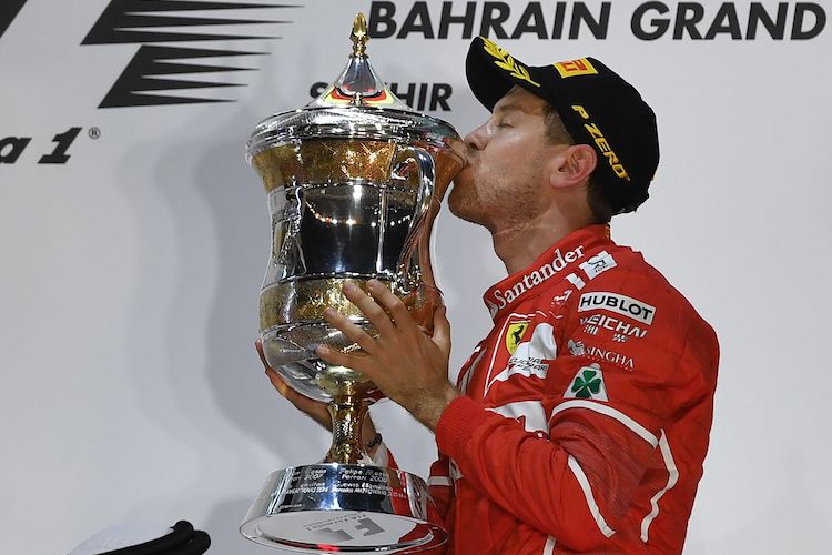 Pebalap Ferrari asal Jerman, Sebastian Vettel, mencium trofi yang didapat setelah memenangi balapan GP Bahrain di Sirkuit Internasional Bahrain, Sakhir, Minggu (16/4/2017).