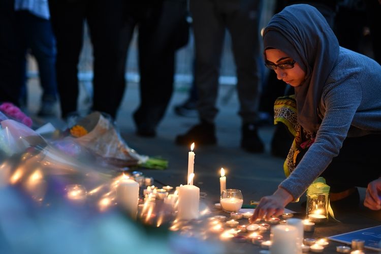 Seorang perempuan menyalakan lilin di Albert Square, Manchester, Selasa (23/5/2017) malam, dalam doa bersama untuk mengenang 22 korban tewas akibat serangan teror di kota itu.