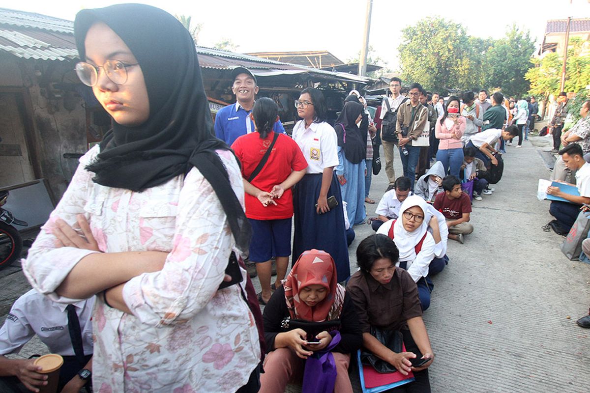 Sejumlah siswa dan orangtua murid antre saat akan mengikuti seleksi Penerimaan Peserta Didik Baru (PPDB) di SMAN 1 Depok, Kota Depok, Jawa Barat, Selasa (18/6/2019). Sistem PPDB Jawa Barat dengan mekanisme berdasarkan sistem jalur zonasi atau pemetaan wilayah sebanyak 90 persen, jalur prestasi lima persen dan jalur perpindahan orang tua wali lima persen tersebut, berlangsung dari tanggal 17-22 Juni 2019.