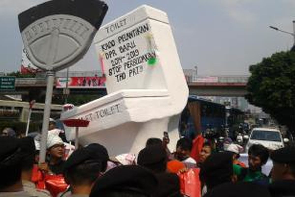 Sekitar lima puluh anggota Komite Aksi Perlindungan Pekerja Rumah Tangga dan Buruh Migran mengangkat kakus dan sapu berukuran besar sebagai simbol pekerja rumah tangga, di depan Gedung DPR/MPR, Jalan Gatot Subroto, Jakarta Pusat, Rabu (1/10/2014).
