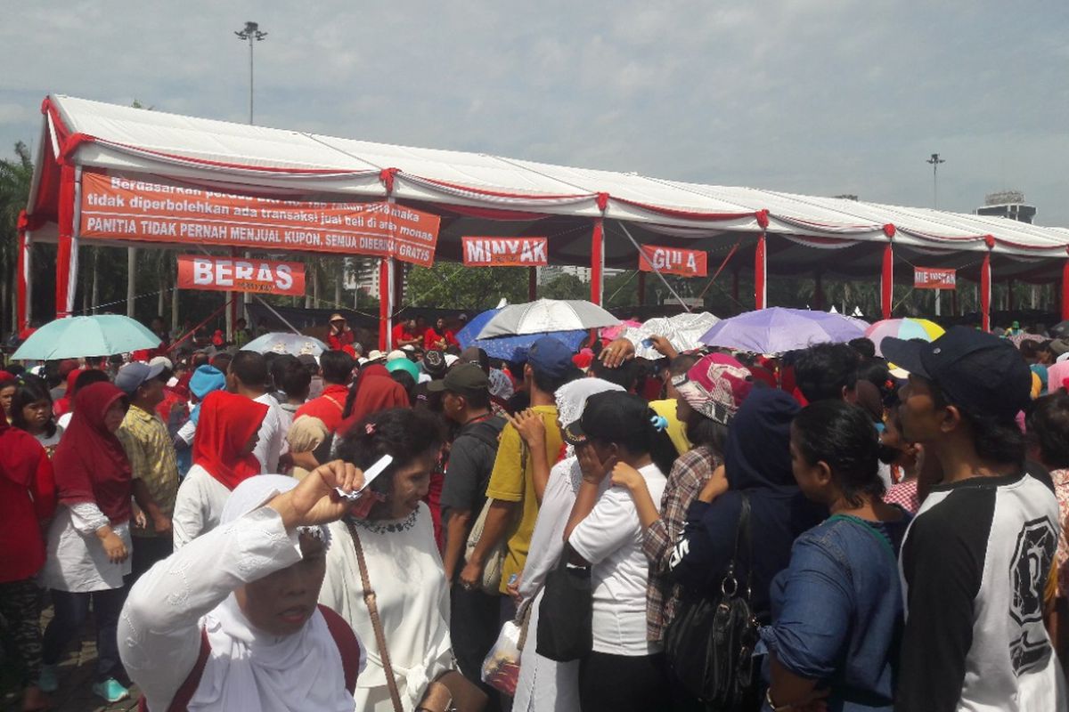 Para warga mengantre sembako dalam acara Untukmu Indonesia di Lapangan Monas, Minggu (28/4/2018).