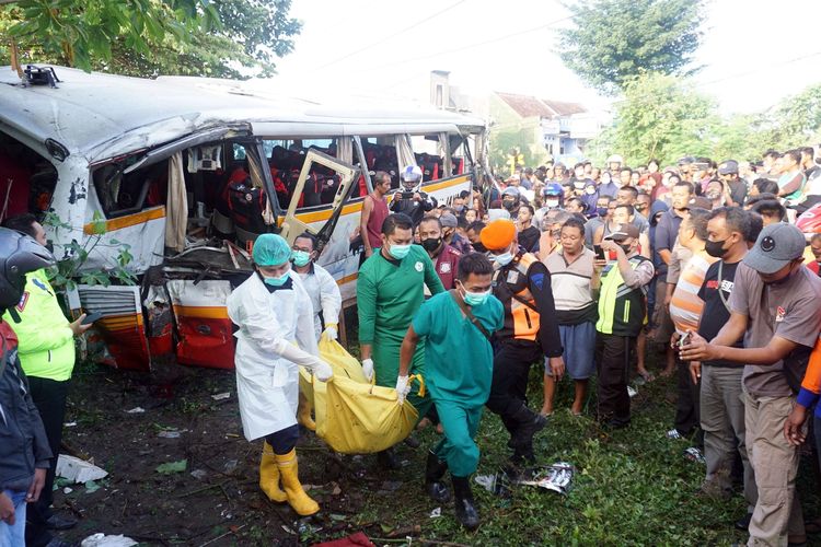 Petugas mengevakuasi jenazah korban kecelakaan bus pariwisata PO Harapan Jaya yang tertabrak KA Rapih Doho di perlintasan kereta api tanpa palang pintu di Desa Ketanon, Tulungagung, Jawa Timur, Minggu (27/2/2022). Kecelakaan yang terjadi sekitar pukul 05.00 WIB itu menyebabkan lima dari 43 penumpang termasuk awak bus meninggal dunia dan 14 lainnya luka-luka dan harus dilarikan ke RSUD dr. Iskak Tulungagung untuk mendapat pertolongan kedaruratan medis.