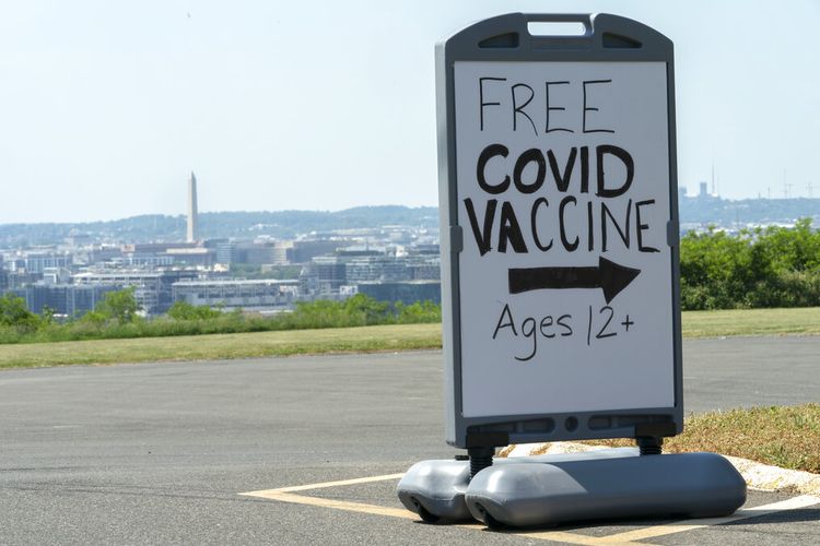 Dalam file foto Rabu, 19 Mei 2021 ini, pusat kota Washington dan Monumen Washington terlihat di belakang tanda yang mengiklankan drive vaksin gratis dengan vaksinasi Pfizer COVID-19 untuk anggota komunitas 12 tahun ke atas di luar sekolah di tenggara Washington . Pada hari Jumat, 16 Juli 2021, 