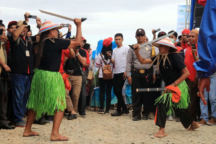 Dua Orang Polahi saling mengayunkan parang tajamnya di arena Festival Pesona Danau Limboto di Kabupaten Gorontalo. Atraksi ini menjadi bagian dari karnaval budaya.