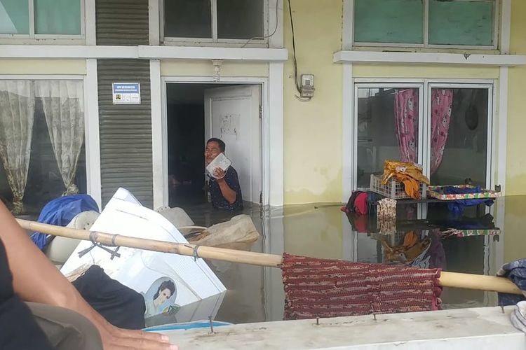 Ansori saat mengevakuasi boneka beruang di rumahnya yang terendam banjir di Garden City Residence Periuk Kota Tangerang, Selasa (4/2/2020)
