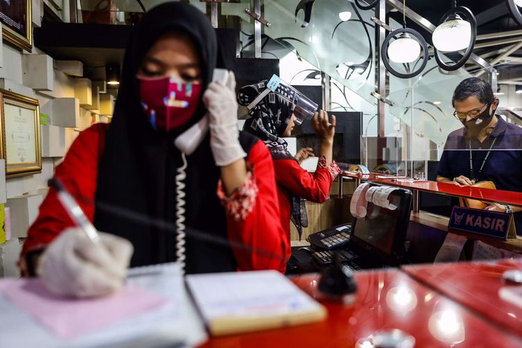 Pelayan menggunakan masker dan pelindung wajah saat melayani pengunjung di kasir di Restoran Sederhana, Bendungan Hilir, Jakarta Pusat, Senin (8/6/2020). Sebagai bagian dari rencana penerapan kenormalan baru 8 Juni 2020, pemerintah DKI Jakarta mengharuskan pengusaha rumah makan membatasi kapasitas maksimal 50 persen, larangan penyajian makanan secara prasmanan dan tetap menerapkan protokol kesehatan.