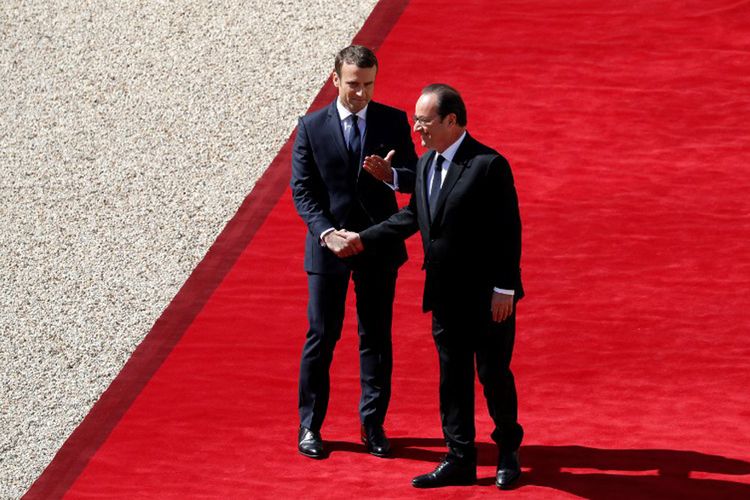 Presiden Perancis Francois Hollande menjabat tangan penggantinya Emmanuel Macron saat ia meninggalkan Istana Presiden Elysee pada akhir upacara serah terima jabatan, dan sebelum pelantikan Macron sebagai Presiden Perancis, Minggu (14/5/2017) di Paris.