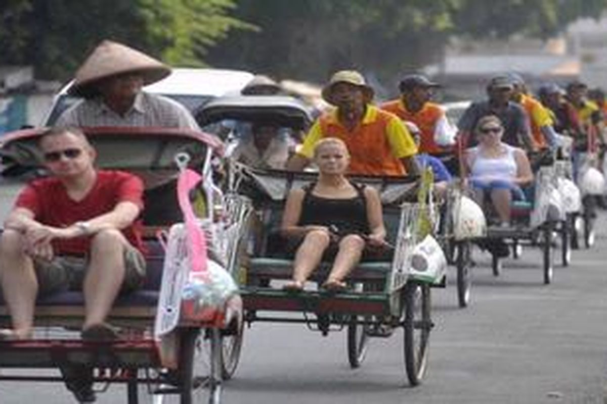 Berkeliling Kota dengan Becak - Wisatawan asing menaiki becak di Jalan Pekapalan, Yogyakarta, Rabu (27/7/2011). Berkeliling kota dengan menggunakan becak merupakan salah satu paket wisata yang banyak ditawarkan berbagai agen pariwisata dan hotel di Yogyakarta.