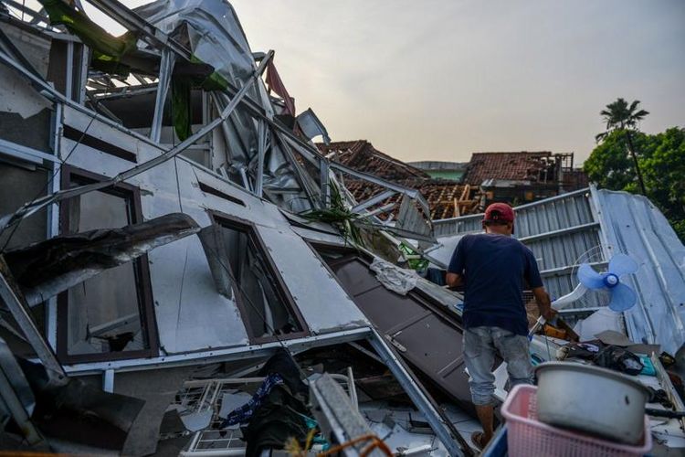 Warga berdiri di antara puing rumah yang hancur akibat angin puting beliung di Desa Sukadana, Kabupaten Sumedang, Jawa Barat, Kamis (22/2/2024).
