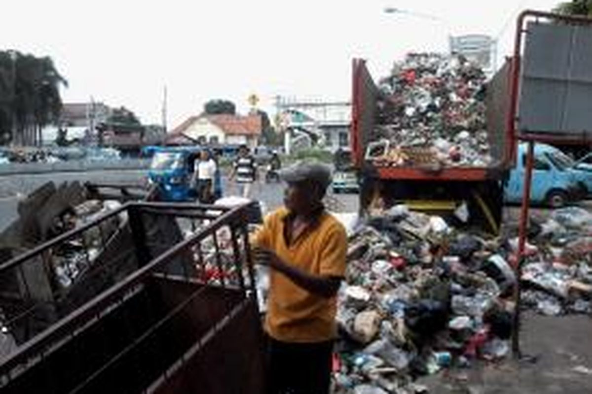 Petugas kebersihan sedang menurun-naikkan sampah dari gerobak ke dalam truk pengangkut, di Kebon Pala, Jakarta Timur.
