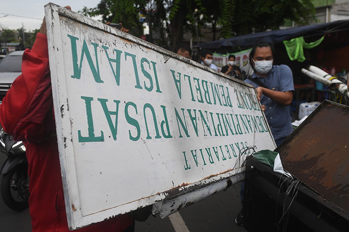 Petugas membongkar atribut-atribut saat melakukan penutupan markas  DPP Front Pembela Islam (FPI) di Petamburan, Jakarta, Rabu (30/12/2020). Polisi dan TNI menutup markas FPI setelah pemerintah memutuskan untuk membubarkan organisasi pimpinan Rizieq Shihab itu.