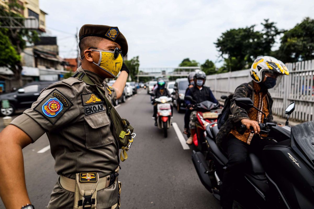 Petugas satuan polisi pamong praja saat patroli penegakan aturan pembatasan sosial berskala besar (PSBB) di Jl. Matraman Raya, Kecamatan Jatinegara, Jakarta Timur, Selasa (19/5/2020). Dalam kegiatan patroli PSBB tersebut, target penegakan untuk masyarakat yang tidak mengunakan masker dijalanan.