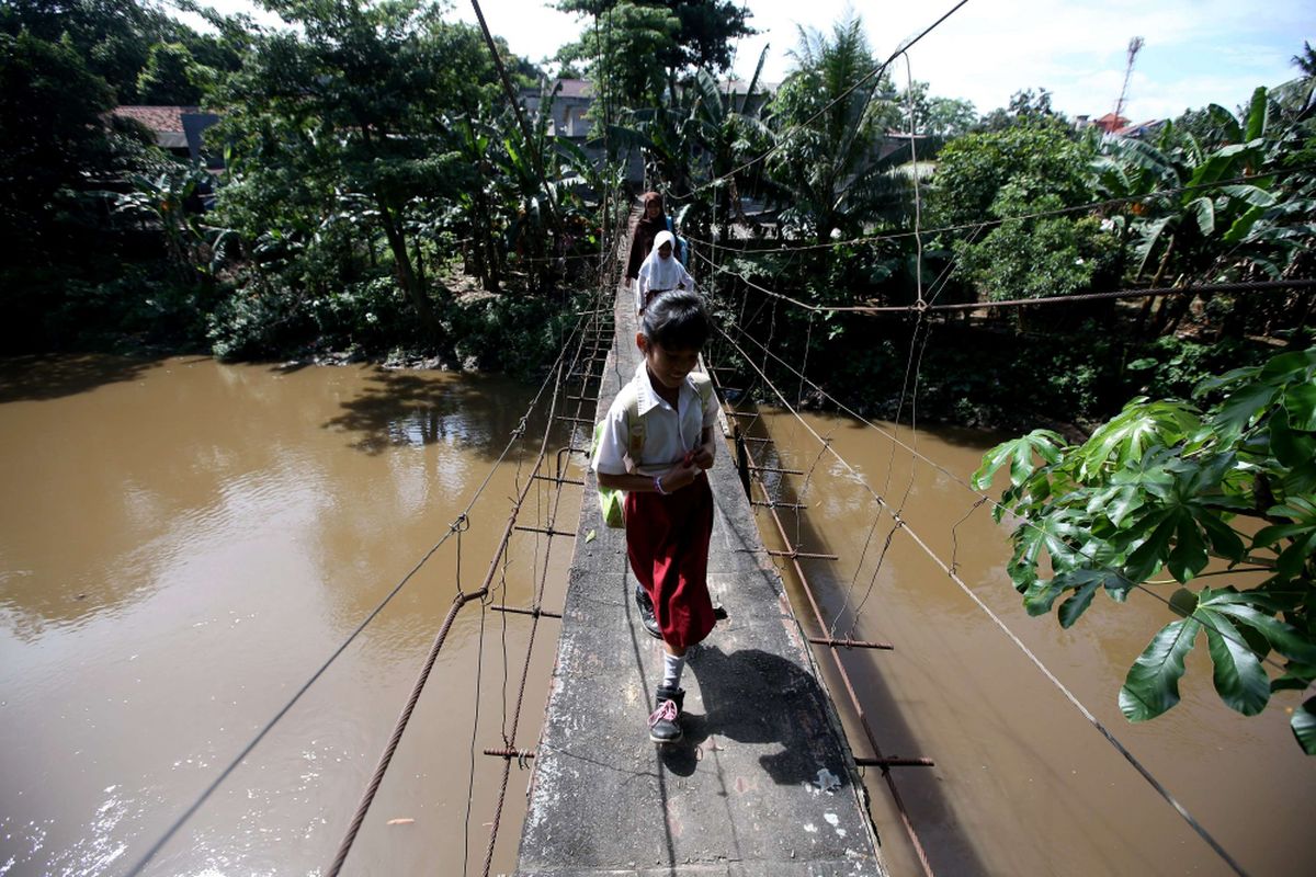 Bocah menyeberang jembatan gantung di Jalan Gardu, Kelurahan Srengseng Sawah, Jagakarsa, Jakarta Selatan, Selasa (23/01/2018). Pemerintah provinsi DKI Jakarta akan segera mengeksekusi pembangunan jembatan di Jagakarsa untuk menggantikan jembatan gantung yang sudah reyot dan tak aman.