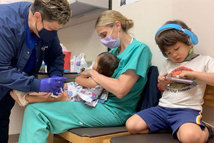 Erin Biro yang memegangi anaknya ketika mendapatkan suntikan vaksin Covid-19 Pfizer di Ochsner Hospital for Children di Jefferson, Louisiana. [Ochsner Hospital Via New York Post]