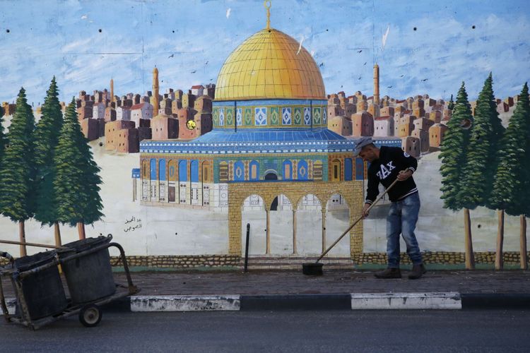 Seorang warga Palestina menyapu jalan pada 7 Desember 2017 di kota Hebron, di Tepi Barat yang diduduki Israel. Otoritas Palestina menyerukan demonstrasi mogok massal di kota Ramallah di Tepi Barat menyusul keputusan Presiden AS Donald Trump untuk mengakui Jerusalem sebagai ibu kota Israel.