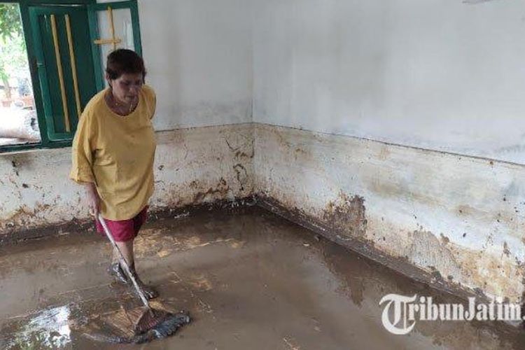 Nurhayati (52) warga Dusun Wringinan, Desa Tambakrejo, Tongas, Kabupaten Probolinggo tengah berupaya membersihkan material lumpur bercampur air di dalam rumahnya, Senin (7/2). Uang tabungan Rp 5 juta milik warga Probolinggo hanyut terbawa banjir.