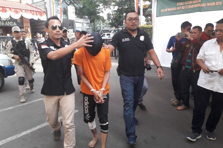 A, pelaku penjambretan terhadap Dirjen Bina Konstrukti Kemenpupera digiring polisi di Mapolres Metro Jakarta Barat, Jumat (29/6/2018).