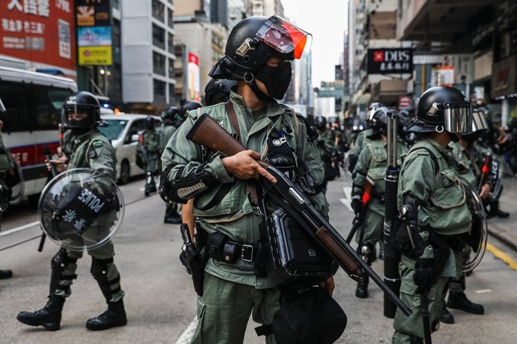 Polisi berjaga-jaga setelah membongkar barikade yang dibangun pengunjuk rasa di sebuah jalan di distrik Mongkok, Hong Kong, Minggu (13/10/2019).
