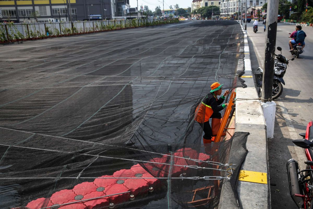 Pekerja memasang jaring-jaring untuk menutupi aliran Kali Sentiong atau Kali Item di Jakarta Utara, Jumat (20/7/2018). Pemasangan jaring-jaring berbahan nilon untuk mengatasi buruknya rupa Kali Item sebelum menerima para atlet Asian Games 2018 dari mancanegara yang akan menginap di Wisma Atlet.