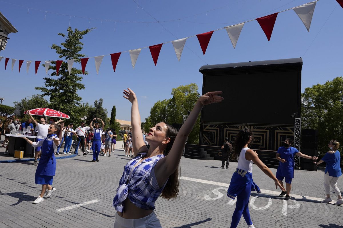 Para penari menyambut kedatangan pengunjung di taman hiburan Cinecitta World, pinggiran Roma, pada hari pembukaan kembalinya, Kamis (17/6/2021). Taman hiburan ini tutup sejak 25 Oktober 2020 saat Italia menerapkan lockdown kedua untuk menangani wabah Covid-19.