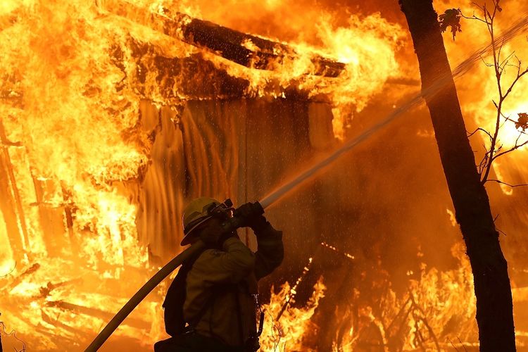 Seorang anggota pemadam kebakaran berusaha menjinakkan Api Camp yang melalap Magalia, California, Amerika Serikat pada Jumat (9/11/2018). Api Camp dan Api Woolsey menjalar dan menewaskan sembilan orang, serta 150.000 orang mengungsi.