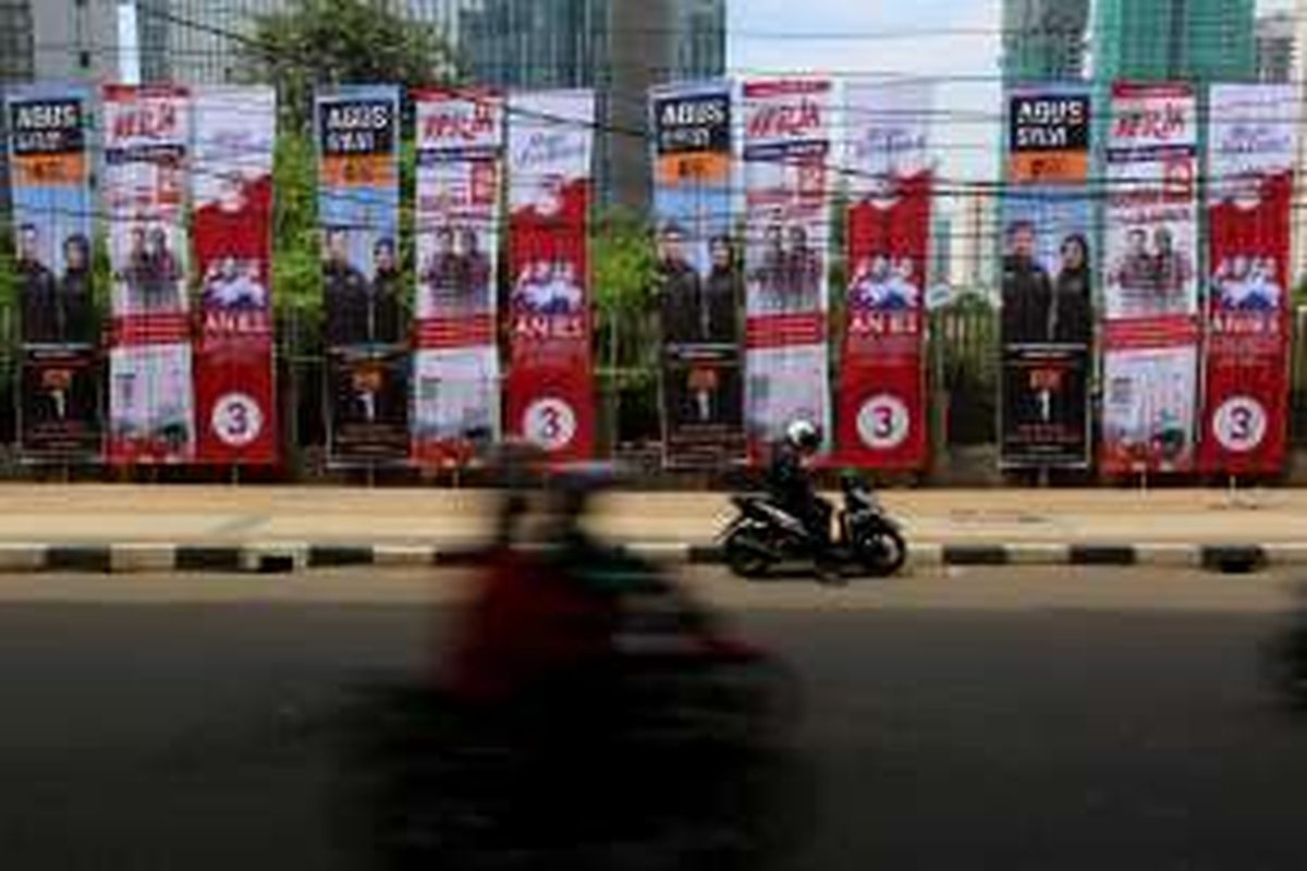 Pengendara sepeda motor melaju di samping baliho bergambar tiga pasangan calon Gubernur dan Wakil Gubernur DKI Jakarta di Jalan Kuningan, Jakarta, Rabu (23/11/2016). KPU DKI Jakarta menyediakan alat peraga kampanye untuk setiap pasangan calon dengan jumlah yang sama, namun apabila masih dirasa kurang mencukupi, masing-masing pasangan calon dibebaskan menambah alat peraga maksimal sebanyak 150 persen dari yang diadakan KPU.