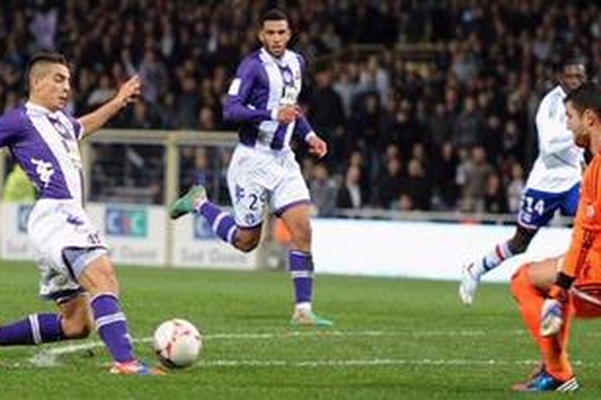 Striker Toulouse, Wissam Ben Yedder (kiri) saat menaklukkan gawang Olympique Lyon yang dikawal Remy Vercoutre pada laga di Stadion Municipal, Toulouse, Minggu (25/11/2012).
