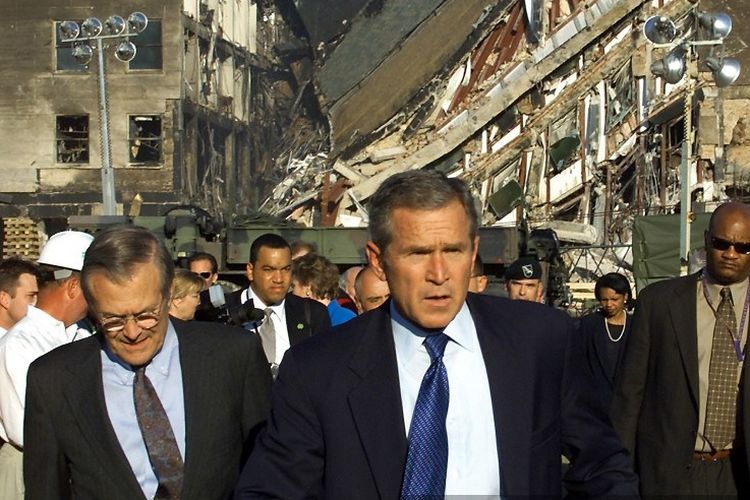 Dalam file foto yang diambil pada 12 September 2001, Presiden AS George W. Bush (tengah) dan Menteri Pertahanan AS Donald Rumsfeld (kiri) mengunjungi area benturan (belakang) di Pentagon di mana sebuah maskapai yang dibajak menabrak bangunan sebagai bagian dari serangan teroris terkoordinasi dengan serangan 9/11 di AS. 