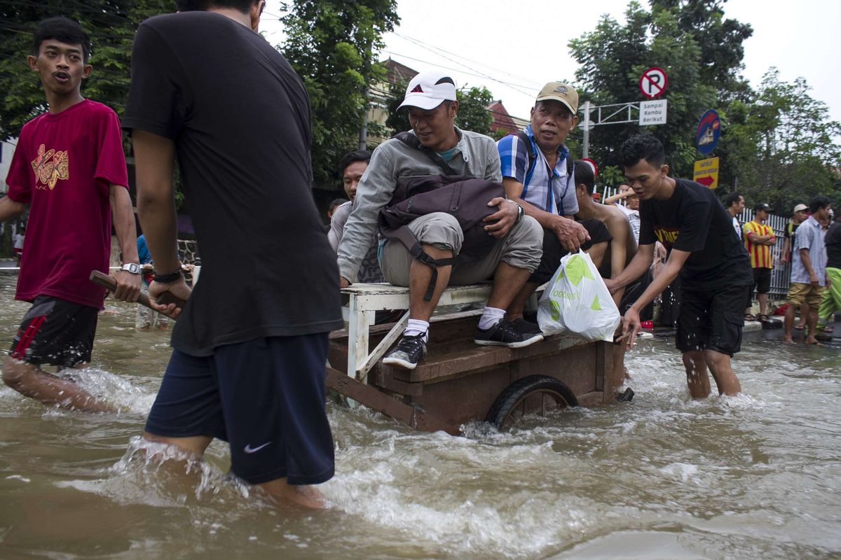 Sejumlah warga mengevakuasi korban yang terendam banjir di Jl. Raya Pondok Gede, Kramat Jati, Jakarta Timur, Rabu (1/1/2020). Luapan air Kali Baru sebabkan wilayah Kramat Jati terendam hingga sebahu orang dewasa.