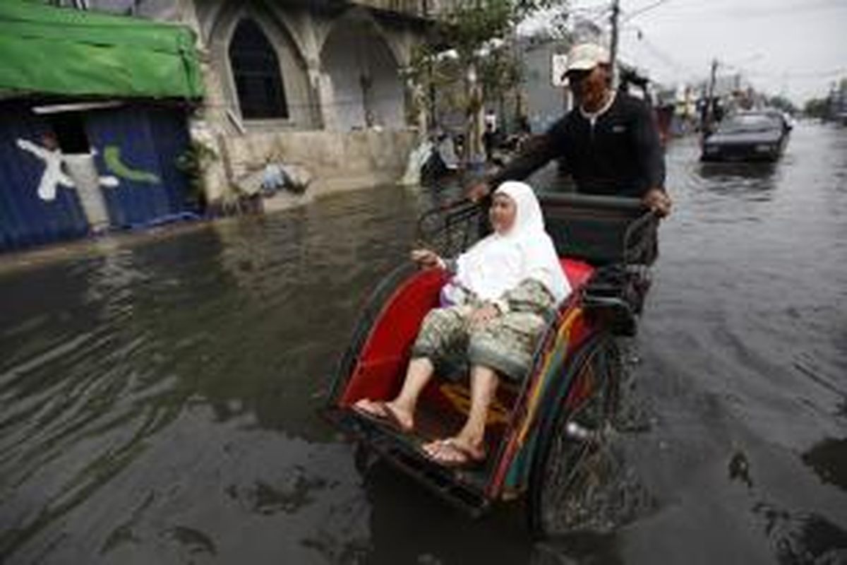 Warga melintasi banjir menggunakan becak di Jalan Kramat Jaya, Jakarta Utara, Rabu (12/3). Hujan deras mengakibatkan banjir setinggi hingga 50 sentimeter di kawasan tersebut sejak pagi. Kompas/Lucky Pransiska (UKI)
