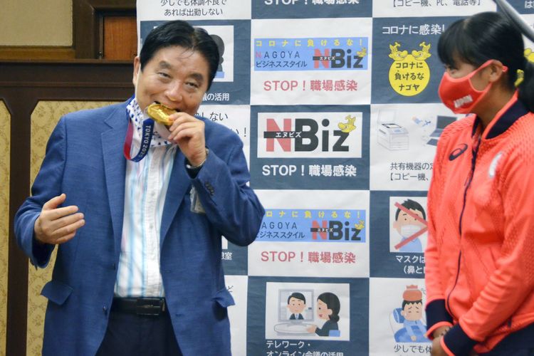Wali Kota Nagoya Takashi Kawamura (kiri) menggigit medali emas atlet Olimpiade Jepang Miu Goto, di kantor pemerintah kota pada 4 Agustus 2021.