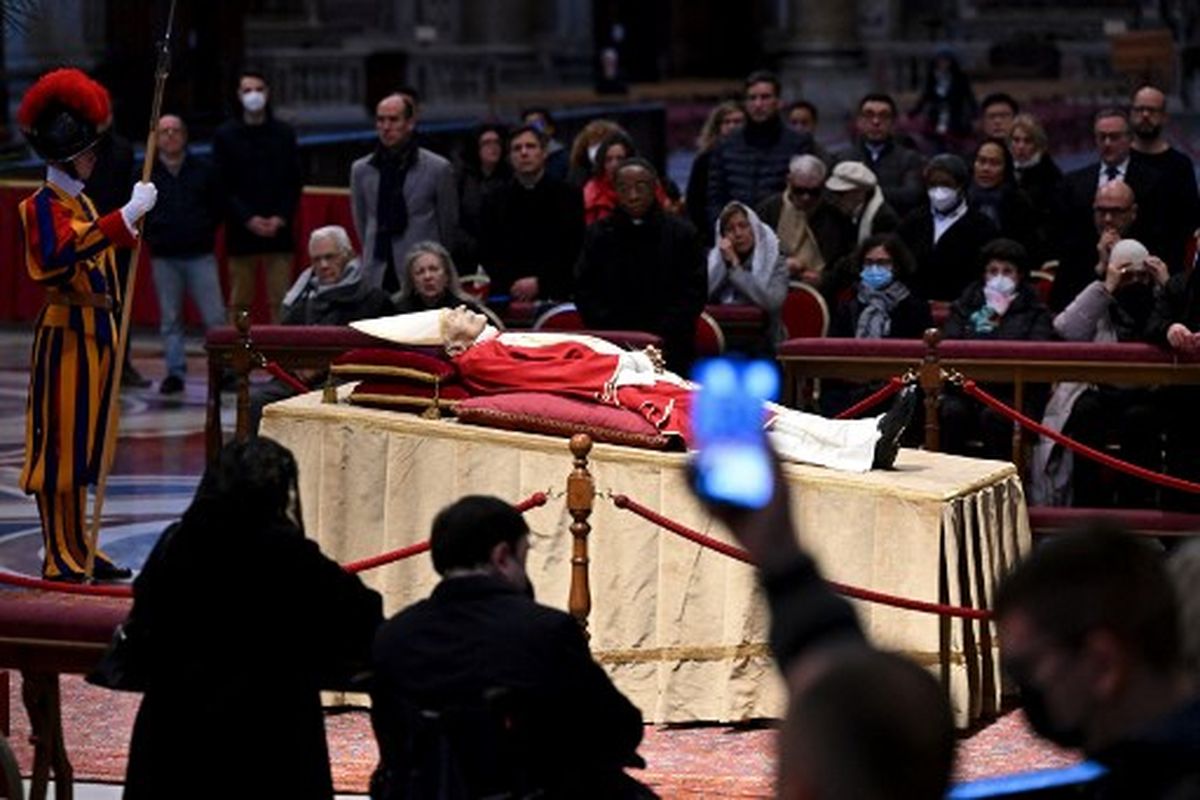 Orang-orang memotret jenazah Paus (Emeritus) Benediktus XVI saat disemayamkan di Basilika Santo Petrus di Vatikan, pada 2 Januari 2023. Paus Benediktus meninggal dunia pada 31 Desember 2022, pada usia 95 tahun. Ribuan umat Katolik mulai memberikan penghormatan terakhir kepadanya pada 2 Januari 2023 di Basilika Santo Petrus di Vatikan sebelum pemakamannya. 