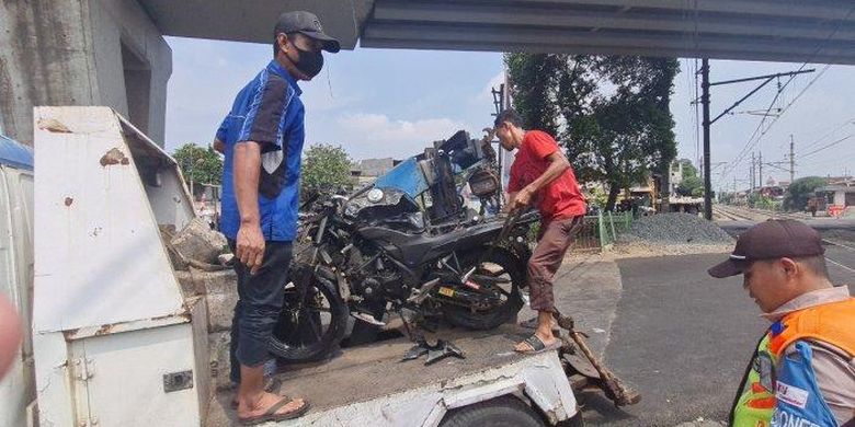 Sejumlah petugas mengangkut motor sport yang ringsek usai ditabrak kereta bandara di pintu perlintasan rel kereta di Pesing, Grogol Petamburan, Jakarta Barat pada Selasa (16/8/2022). 
