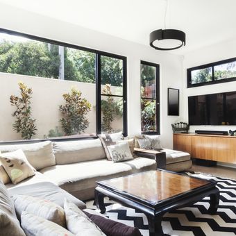 Ilustrasi ruang tamu dengan TV yang dipadukan dengan aksen warna monokrom, karpet di ruang tamu. 
